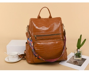 Detail of caramel brown crocodile texture backpack with stylish detachable colorful strap