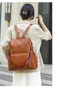 Close-up of brown crocodile texture backpack with colorful ethnic woven strap detail