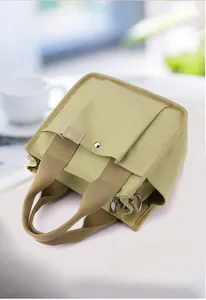 Detail of light olive canvas tote backpack featuring flap pockets and khaki webbing straps