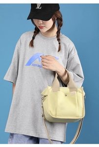 Detail view of yellow canvas crossbody bag with wide woven handle and functional pockets
