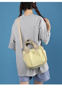 Rear view of a model wearing a large yellow canvas tote bag with wide shoulder strap