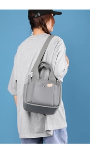 Detailed view of gray canvas multi-pocket crossbody bag with adjustable strap on model