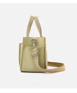 Detailed macro view of green canvas tote bag with adjustable shoulder strap and side pocket