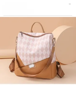 Detail view of beige quilted backpack showing brown leather trim and metal zip hardware
