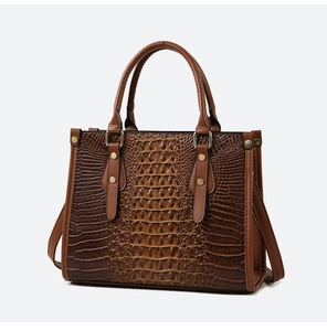 Detail of crocodile embossed pattern on a brown tote bag with gold metal hardware