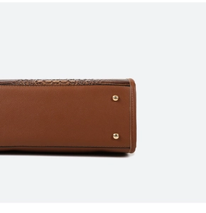Detail view of brown faux leather handbag with crocodile pattern and gold metal studs