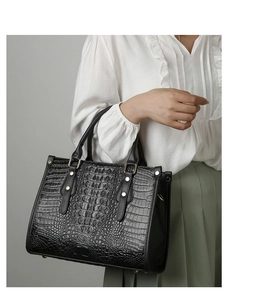 Detail of black crocodile pattern tote bag with gold studs and protective bottom feet