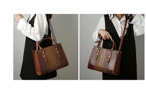 Detail of brown faux crocodile leather tote bag with gold hardware and dual handles