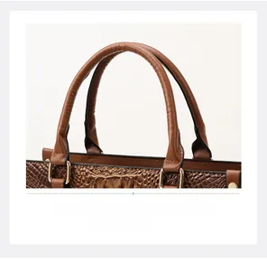 Detail of brown crocodile pattern handbag with golden metal rings and sturdy double handles