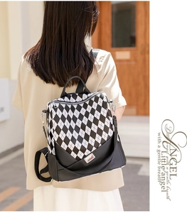 Outdoor shot of a black and white checkered backpack with adjustable straps and logo