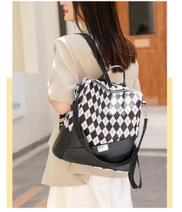 Detail of black and white checkered quilted backpack on model in urban street setting