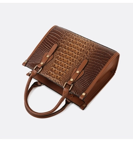 Detail of brown tote bag showing crocodile pattern texture and gold hardware accents