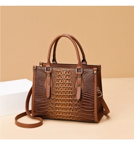 Close-up of brown crocodile pattern embossed leather handbag with bronze hardware details