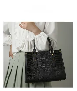 Detail shot of black crocodile embossed tote bag with metal rivets and sturdy handles