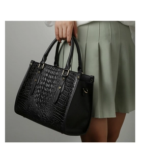 Detail of black crocodile texture tote bag with gold hardware and top handles