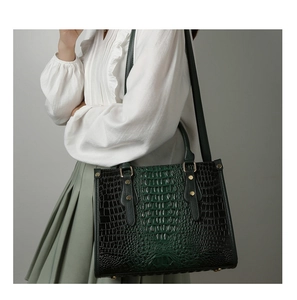 Detail of dark green crocodile embossed tote bag with gold studs and shoulder strap