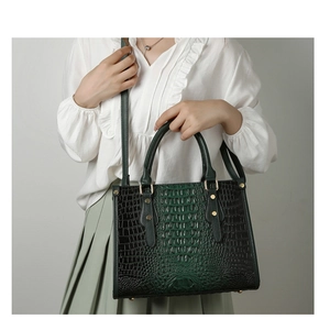 Detail of gradient dark green faux crocodile leather handbag with gold hardware and rivets