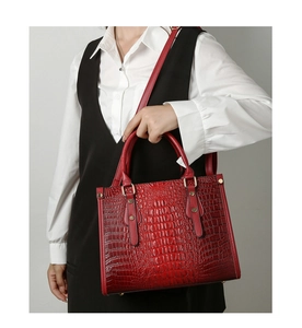Model wearing red crocodile embossed tote bag with adjustable shoulder strap