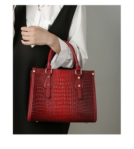 Detail of red crocodile texture handbag with gold metal accents and dual handles