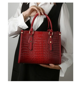 Detail of dark red crocodile embossed leather tote with metal rivets and sturdy handles
