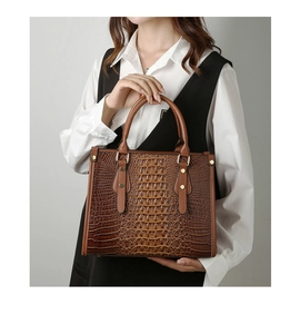 Close-up of crocodile textured brown leather tote bag with elegant gold metal rivets