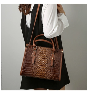 Brown crocodile pattern tote bag with golden hardware shown in a street style outfit