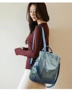 Detail of grey-blue contrast backpack with matte leather texture and navy blue stitching