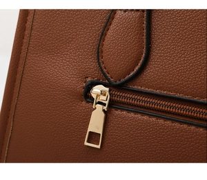 Close-up of brown pebbled leather texture and light gold zipper on the tote bag