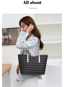 Détail d'un grand sac cabas noir à motif quadrillé doré porté à l'épaule pour femme
