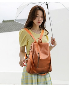 Detail of orange faux leather backpack with metallic zippers and textured finish