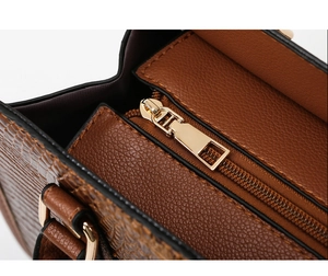 Detail shot of a dark brown embossed leather tote with premium light gold metal hardware