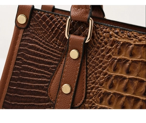 Macro shot of brown faux crocodile leather texture and golden D-ring hardware on bag