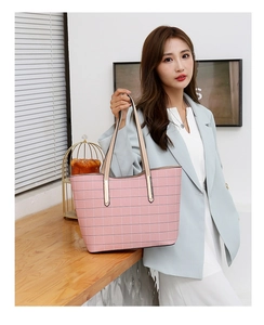 Sac fourre-tout à carreaux roses avec détails en métal doré tenu par un mannequin chic