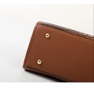 Detail of lychee pattern leather handbag with croc-embossed trim and gold-tone base studs