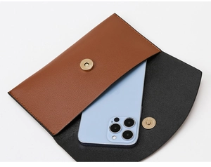 Detail view of brown pebbled leather wallet with gold magnetic snap button and phone slot