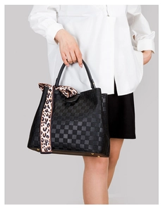 Détail d'un sac à main noir à damier avec foulard léopard en soie sur la poignée