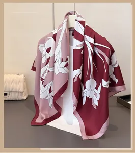 Detail of silk-like floral scarf in burgundy and pink draped over a white display stand