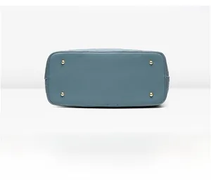 Détail du dessous du sac bleu en cuir grainé avec quatre pieds de protection dorés
