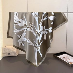 Close-up of olive green square silk scarf featuring white floral iris print patterns