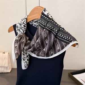 Detailed pattern of small square silk scarf with geometric bird prints on a wooden hanger
