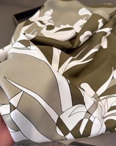 Close-up of silk-textured floral scarf featuring olive green abstract botanical prints