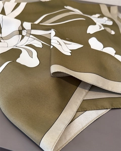 Detail of olive green silk scarf with artistic white iris floral print and smooth texture