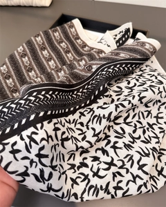 Detailed pattern view of a bird print and geometric scarf on a black display tray