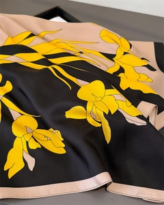 Detailed view of yellow floral print on black silk scarf with elegant fabric drapes