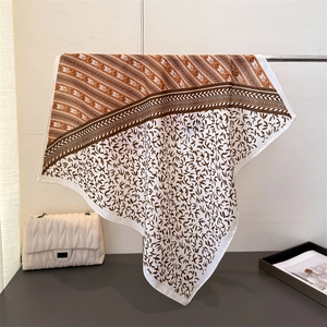 Lightweight square scarf with brown leaf pattern and herringbone texture on a display stand