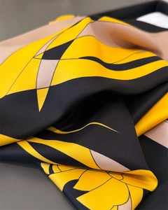 Close-up of faux silk scarf with yellow and black geometric patterns and twill texture