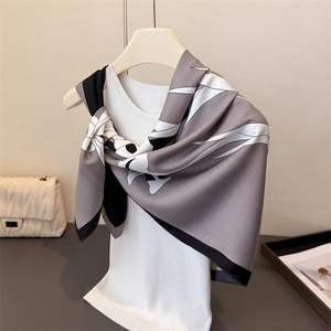 Close-up of silk-textured square scarf with abstract white floral print and draped hem