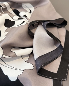 Macro shot of silk-like satin scarf featuring vintage floral print and rolled hem detail