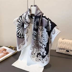 Foulard en soie artistique à motif chevrons et fleurs noué sur un pull en tricot blanc