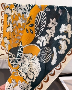 Détail d'un foulard effet lin avec motifs floraux en jaune et bleu sarcelle